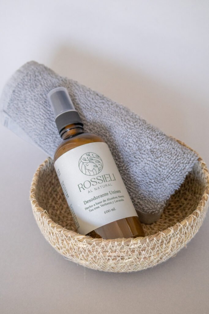 Desodorante Unisex de Rossieli Al Natural en una canasta de fibra natural junto a una toalla