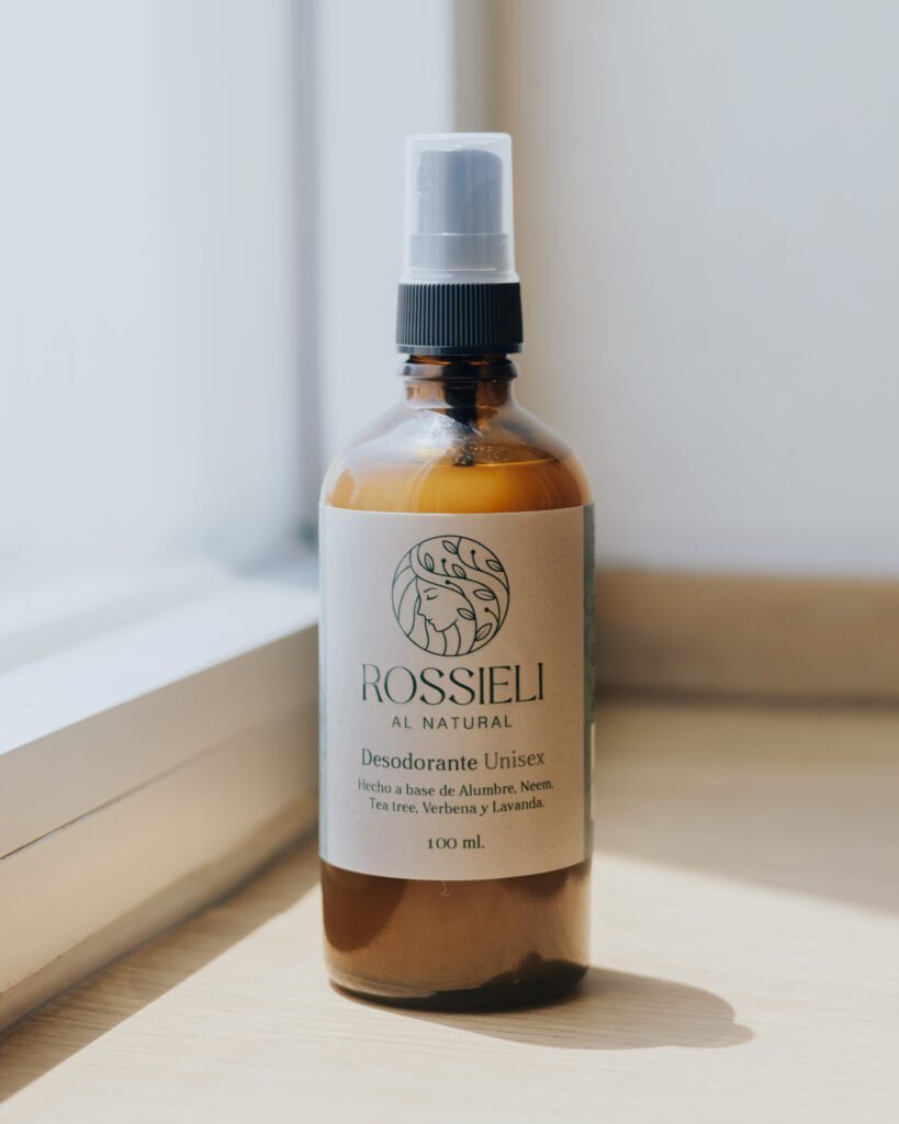 Desodorante Unisex de Rossieli Al Natural sobre una repisa de madera junto a una ventana
